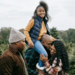 cheerful black family having fun together among spruce