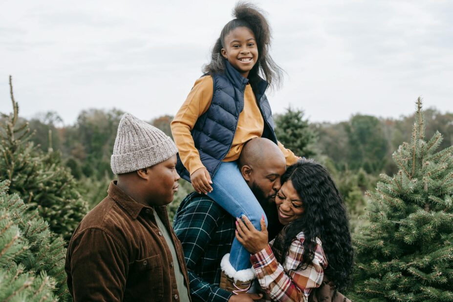 cheerful black family having fun together among spruce