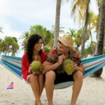 a couple drinking coconut sitting on the hammock
