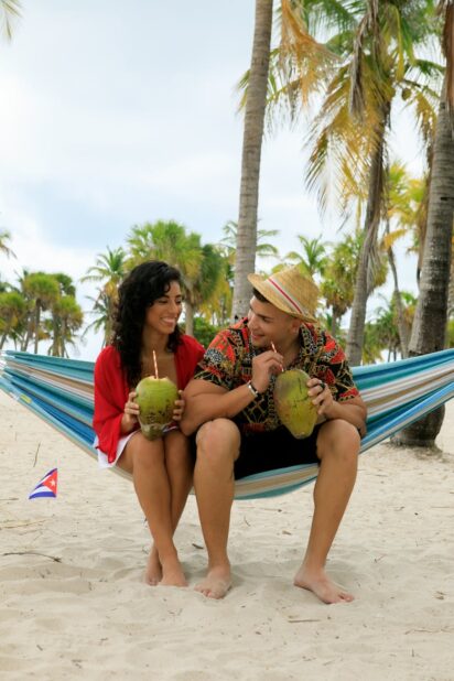 a couple drinking coconut sitting on the hammock