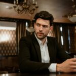 man in black suit jacket sitting at the bar counter
